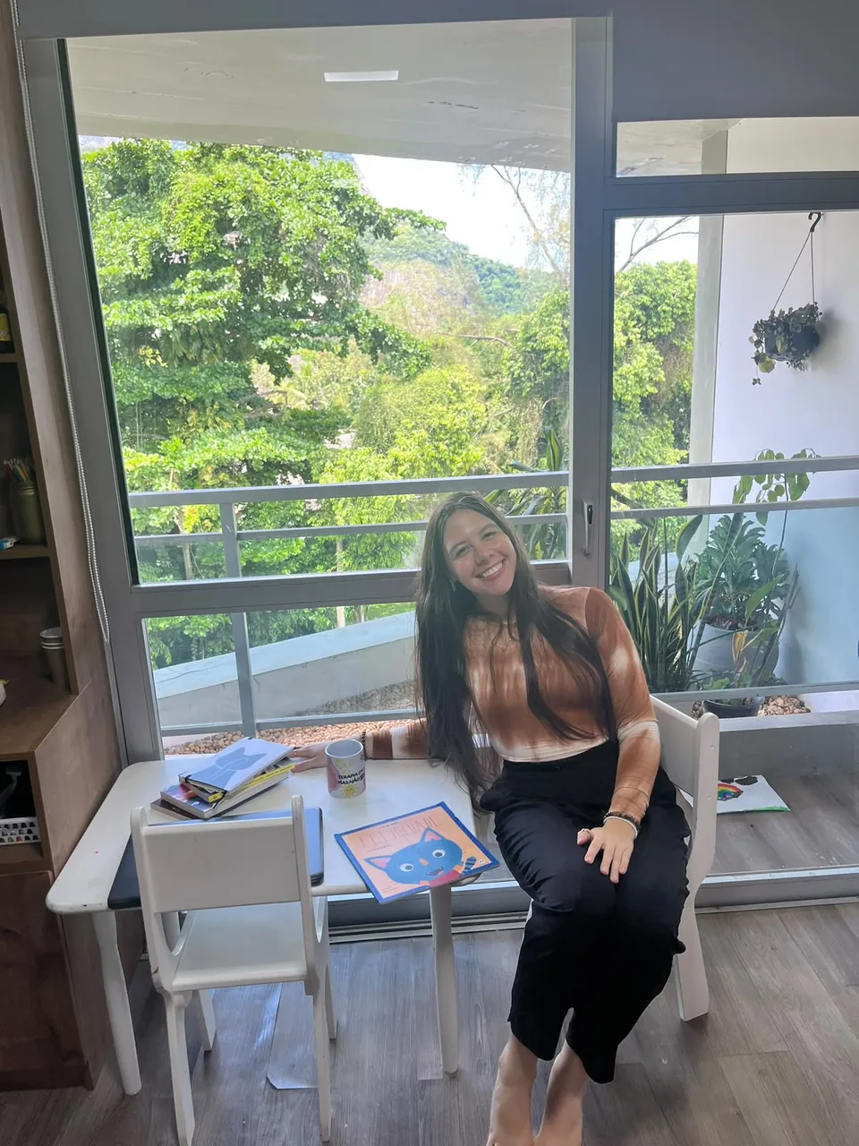 Maria Eduarda Mendonça no cantinho de leitura infantil, com vista para o verde da Barra da Tijuca