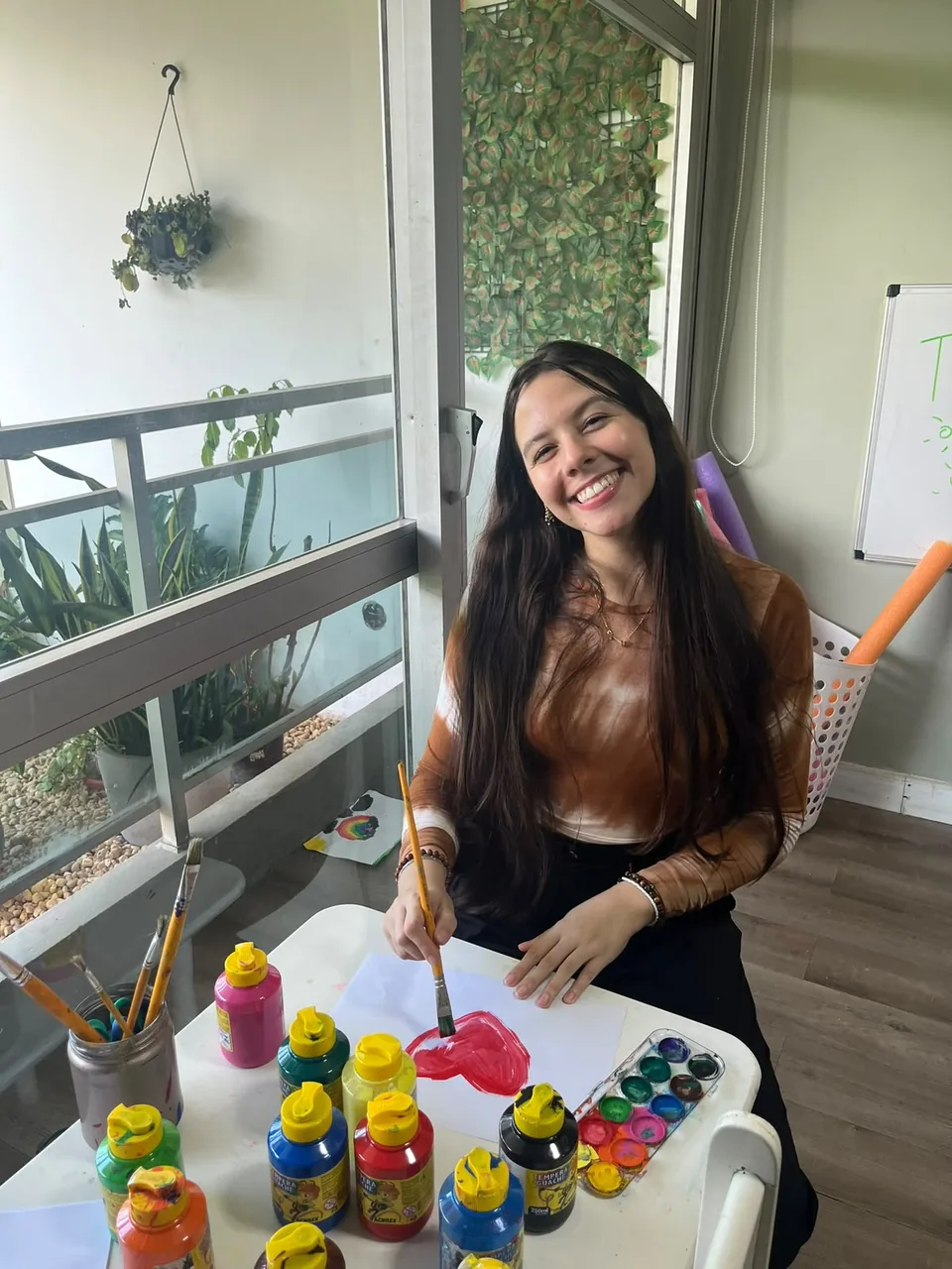 Maria Eduarda Mendonça em atividade de pintura com tintas guache no espaço infantil do consultório